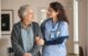 A nurse holding the hand of an old woman.