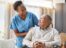 A man in a wheelchair being assisted by a nurse.