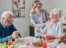 An old couple sitting around a table with an expert nurse taking care of them.