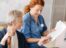 An Americare nurse in a blue shirt sitting next to an older woman and explaining the reports.