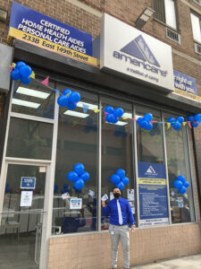 An Americare doctor standing in front of the Americare office with blue balloons.