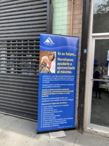 A signboard of Americare on a sidewalk in front of a building.