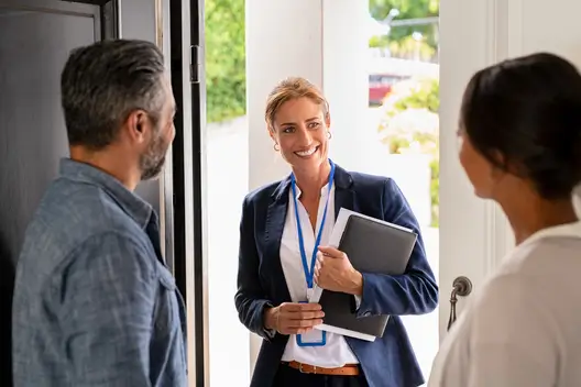 A certified Attencia caregiver talking to a couple at the door.