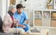 An Americare doctor and woman sitting on a couch in a living room.