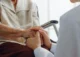 A woman holding a man's hand in a doctor's office.