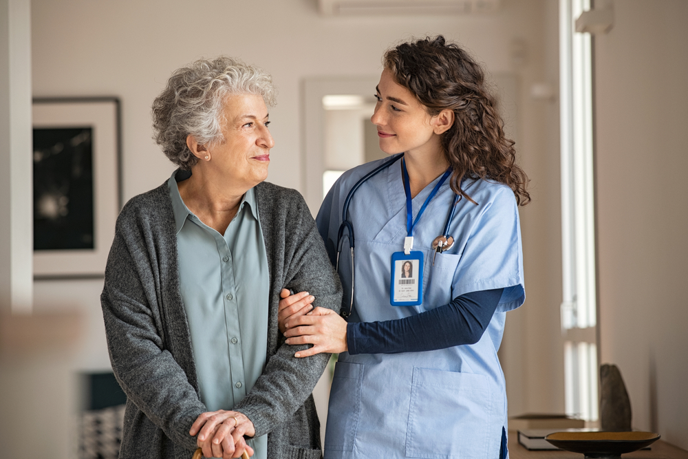 Younger Woman Helping Older Woman in Nursing Home