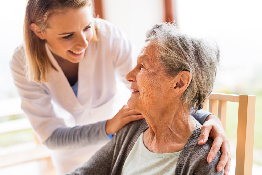 Female Nurse Smiling at Senior Woman Sitting