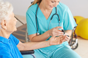 Female Caregiver Helping Elderly Diabetic Patient Test Their Blood