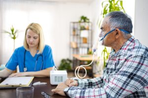 Caring nurse assists elderly man with breathing treatment