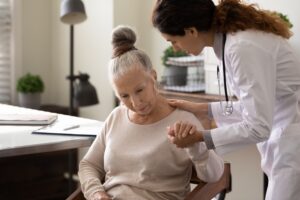 Medical caregiver helping elder patient to cope with Parkinson’s diagnosis
