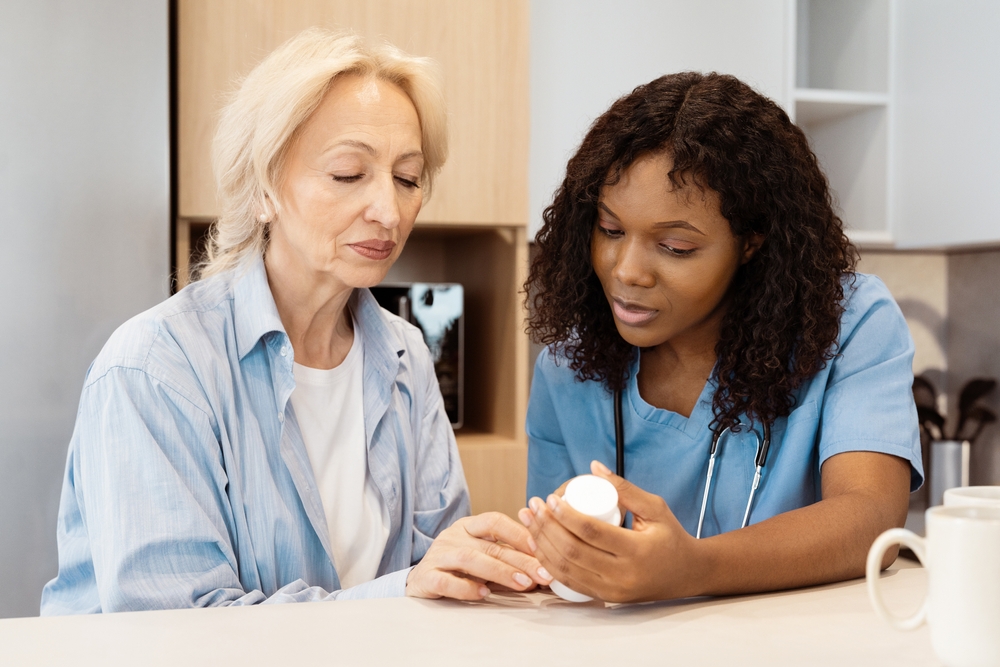 Home health aide reviewing medication with a senior woman.